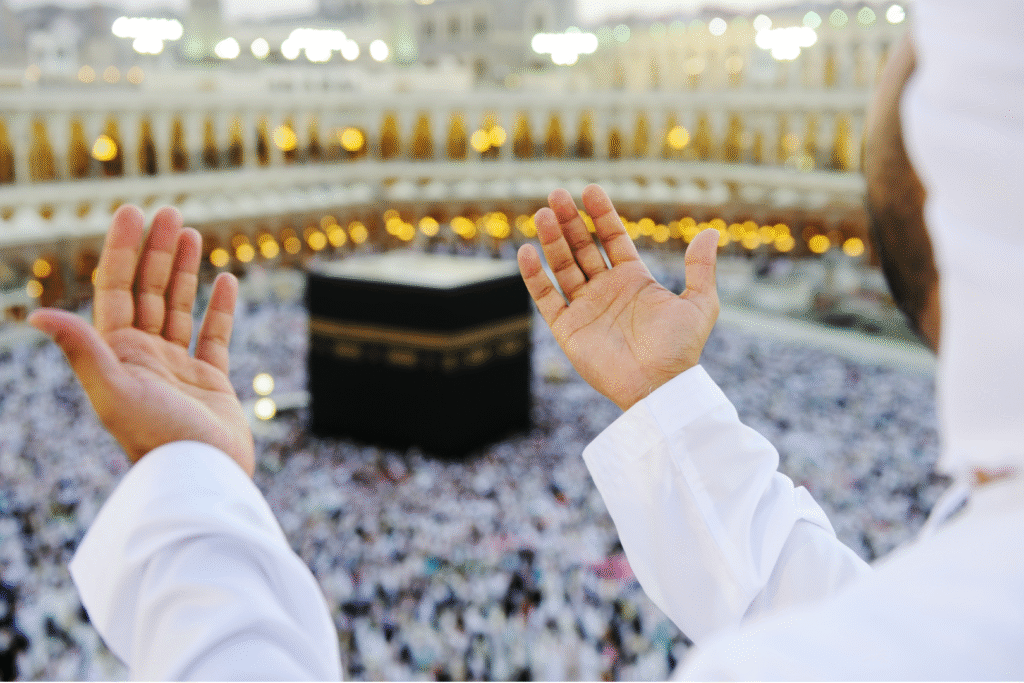 Pèlerin levant les mains en prière face à la Kaaba pendant l’Omra à La Mecque — image utilisée par Colibri Voyage pour ses voyages Omra depuis le Maroc.