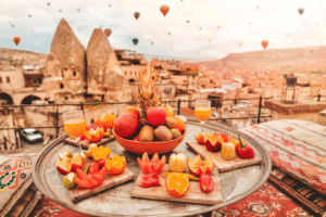 Petit-déjeuner turc avec fruits frais sur un plateau à Cappadoce, Turquie, lors d'un voyage organisé avec montgolfières et formations rocheuses en arrière-plan.