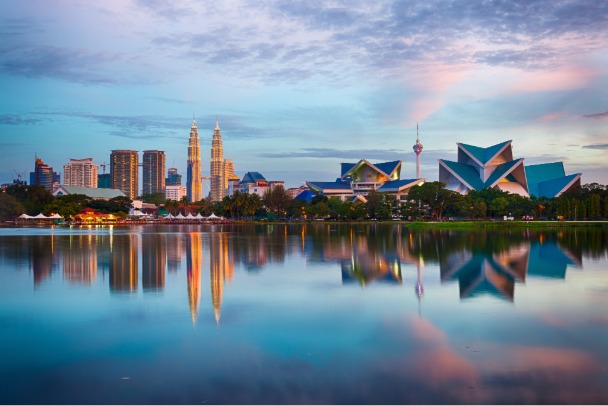Panorama de Kuala Lumpur au coucher du soleil avec les tours Petronas et un lac miroir, prise lors d'un voyage organisé en Malaisie.
