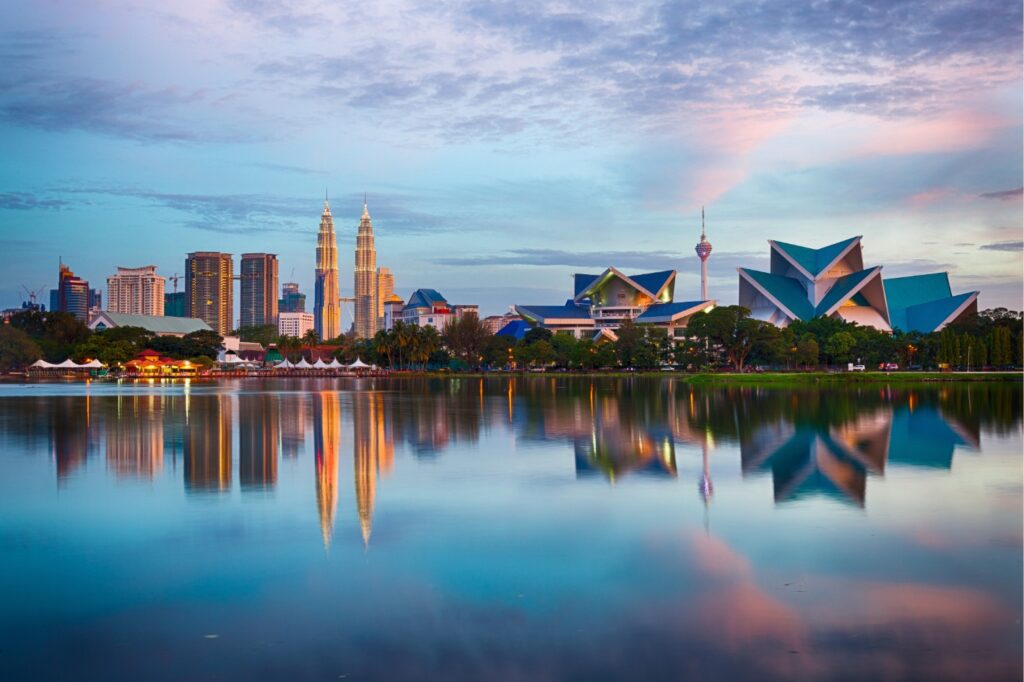Panorama de Kuala Lumpur au coucher du soleil avec les tours Petronas et un lac miroir, prise lors d'un voyage organisé en Malaisie.